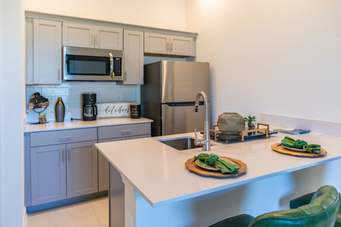 Moderne compacte loftkeuken met koelkast en gootsteen in één ruimte.