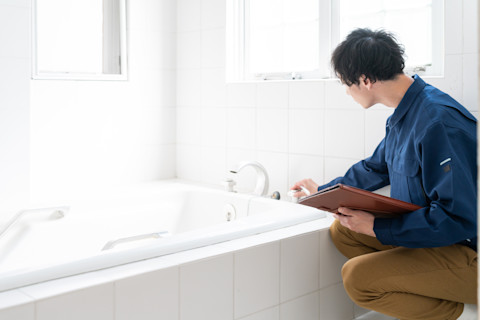 Vakman inspecteert bad en waterleidingen in badkamer.