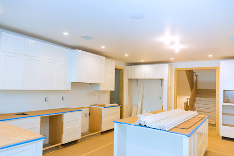 Keuken in renovatie met witte keukenkasten en lege werkbladen, klaar om gewrapt te worden.
