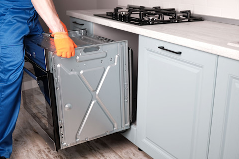 Een oven wordt door een keukenmonteur in de keuken geplaatst.