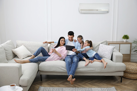 Gezin zit samen op de bank in de woonkamer en profiteren van het efficiënt gebruiken van een airco in huis