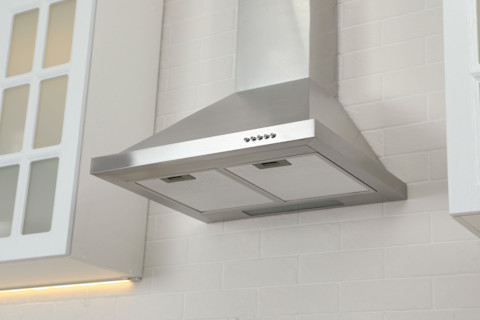 Wandafzuigkap tegen een witte bakstenen muur in een moderne keuken, strak design in beeld.