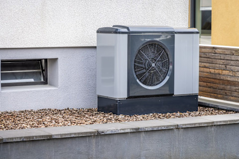 Moderne luchtbron warmtepomp gemonteerd aan de buitenmuur van een woning.