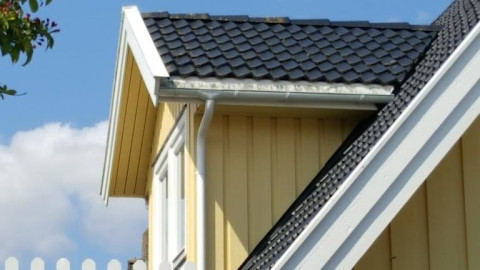 boeidelen op een geel huis met zwarte dakpannen