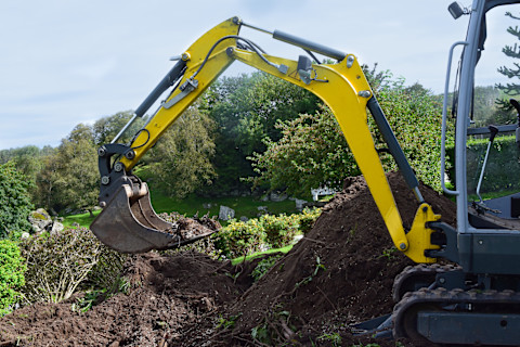 Graafmachine graaft grond af ter voorbereiding op bestrating of fundering.