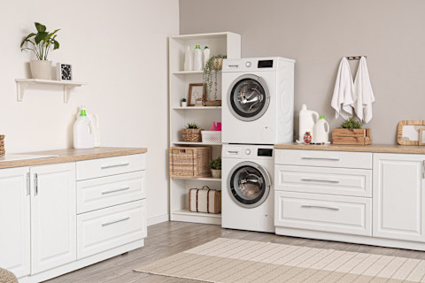 Witte wasmachines in een lichte bijkeuken met open planken en decoratieve accenten voor een functionele uitstraling.