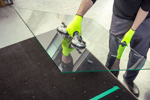 Man tilt voorzichtig een raam van glas met zuignappen tijdens glaszetten voor een nauwkeurige en vakkundige installatie.