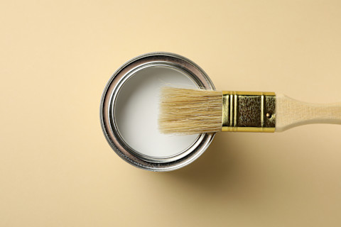 Verfblik en kwast op een beige achtergrond, klaar voor schilderwerk
