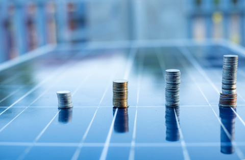 Een munt op zonnepanelen als symbool voor besparing en investering in zonne-energie.