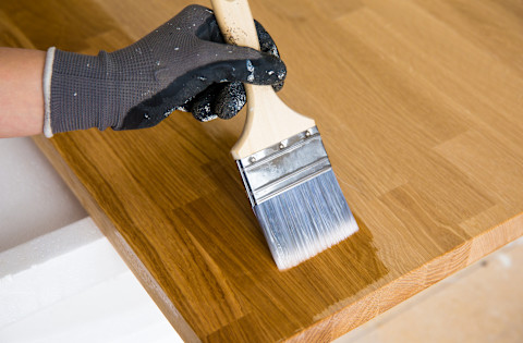 Persoon brengt olie aan op houten keukenblad ter bescherming en onderhoud.