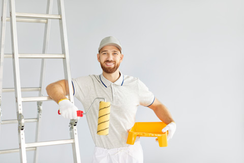 Professionele schilder met ladder in werkkleding klaar voor schilderklus aan huis