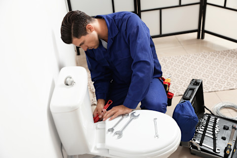 badkamer installateur installeert een wit toilet in een badkamer