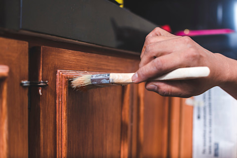 Klusser brengt een verse vernislaag aan op hout, met precisie en aandacht voor detail.