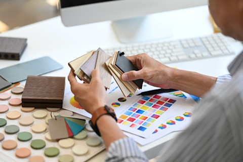 Ervaren interieurontwerper bekijkt kleurstalen, staande in een inspirerende ontwerpstudio.