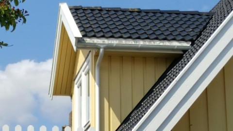 boeidelen op een geel huis met zwarte dakpannen