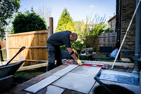 Een stratenmaker die tegels legt in de tuin