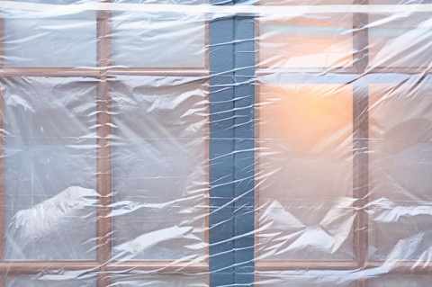 Raam afgedekt met doorzichtige plastic folie als tijdelijke raambekleding tijdens renovatie.
