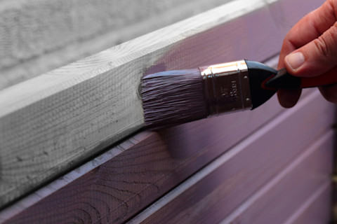 Houten oppervlak dat zorgvuldig wordt afgewerkt met beits voor een diepe kleur en bescherming.