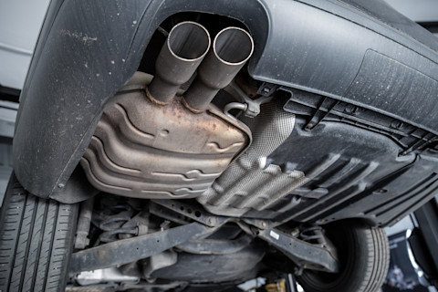 Onderzijde van een auto met zicht op het roetfilter en uitlaatsysteem tijdens onderhoud