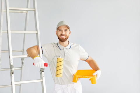 Professionele schilder met ladder in werkkleding klaar voor schilderklus aan huis