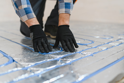 installateur monteert leidingen voor vloerverwarming tijdens een renovatie.