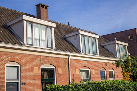 Traditionele woning met een houten dakkapel voorzien van ramen en dakpannen.
