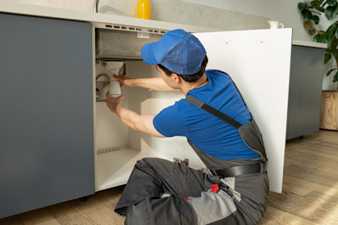 vakman werkt aan het installeren van een sifon van een nieuwe wastafel