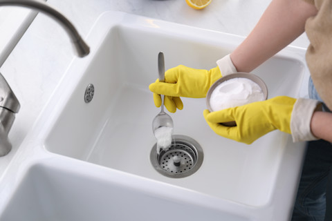 Hand gooit baksoda in de wasbak