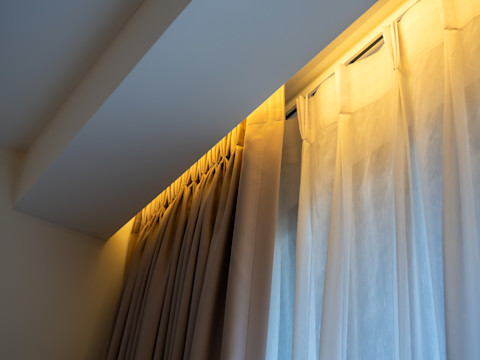 Beige verduisteringsgordijn gecombineerd met wit linnen voor lichtdoorlatende en stijlvolle raamdecoratie.