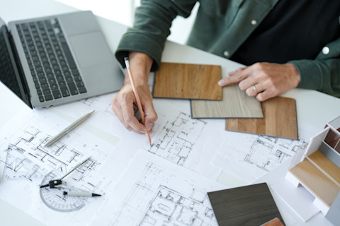Man bespreekt interieurontwerp in een moderne keuken met creatieve projecttekeningen op tafel.