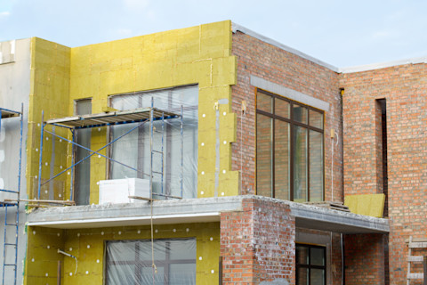 Een buitenkant van een flatgebouw appartement waarbij nieuwe voorgevel isolatie wordt aangebracht.
